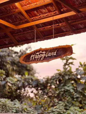 a sign that says happyland hanging from a roof at Happy Land in Shoranūr