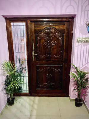 a wooden door in a room with two potted plants at Shivalaya Stays - Coimbatore in Coimbatore