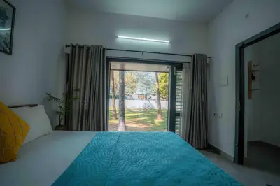 a bedroom with a bed and a large sliding glass door at Cabana by Grha - Charming Cottage at Kappad Beach in Kozhikode