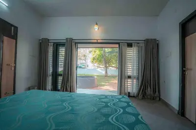 a bedroom with a bed and a large sliding glass door at Cabana by Grha - Charming Cottage at Kappad Beach in Kozhikode