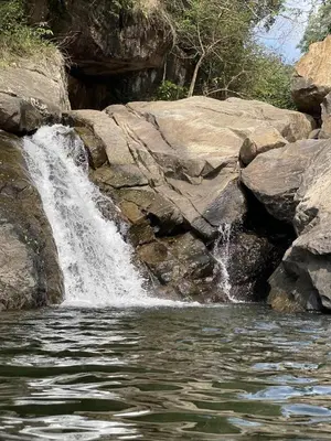 a waterfall on the side of a pool of water at Wetlands Wayanad Pool Resort with Natural Waterfalls in Padinjarathara