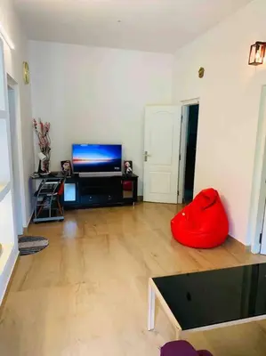 a living room with a flat screen tv and a red pillow at Aanandam - An Independent Villa in 1 Acre Farm in Wayanad