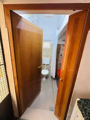 a bathroom with a toilet and a wooden door at Aanandam - An Independent Villa in 1 Acre Farm in Wayanad