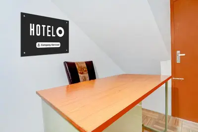 a table with a chair and a sign on a wall at Super Hotel O Avinashi Road Coimbatore in Coimbatore