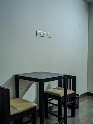 a glass table with two stools in a room at Raaha Residency in Kozhikode