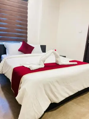 a bedroom with two beds with red and white sheets at Raaha Residency in Kozhikode
