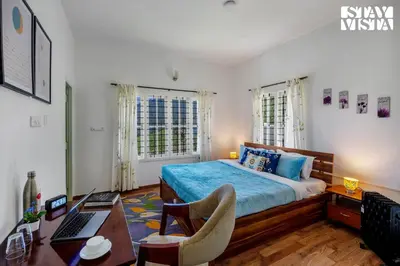 a bedroom with a bed and a desk with a laptop at StayVista at Orion's Crest ooty including breakfast in Ooty