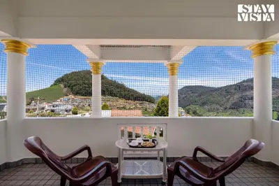 a balcony with chairs and a table with a view at StayVista at Orion's Crest ooty including breakfast in Ooty