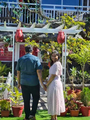 a man and a girl holding hands in front of a garden at S & B Dreams House in Munnar