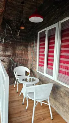 two white chairs and a table and two windows at S & B Dreams House in Munnar