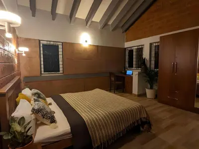 a bedroom with a bed and a desk and windows at Red Rock Villa, Virajpet, Coorg in Virajpet