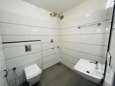 a white bathroom with a toilet and a sink at RIO ROOMS Medical College in Kozhikode