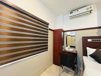 a bedroom with a bed and a desk and a chair at RIO ROOMS Medical College in Kozhikode