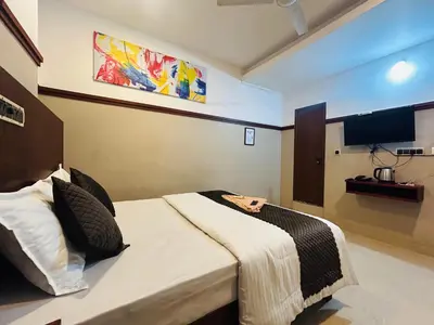 a bedroom with a bed and a tv on the wall at RIO ROOMS Medical College in Kozhikode