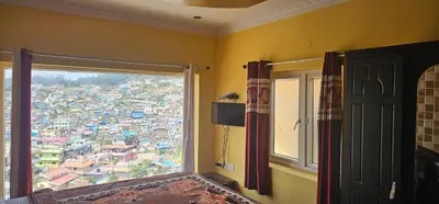 a room with a window with a view of a city at OOTY STAY AWHILE in Ooty