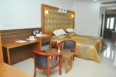 a hotel room with a bed and a desk and a desk at Kallada Mamatha Motels in Kunnamkulam