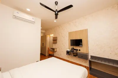 a bedroom with a white bed and a tv at THE CONTINENTAL INN & SUITES in Mysore