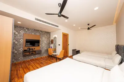 a bedroom with two beds and a flat screen tv at THE CONTINENTAL INN & SUITES in Mysore
