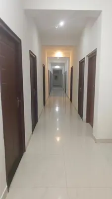 a hallway of a building with brown doors and tile floors at ARIVU LODGE AC in Anaimalai