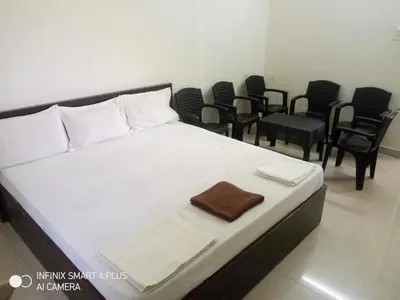 a bedroom with a bed with chairs in a room at ARIVU LODGE AC in Anaimalai