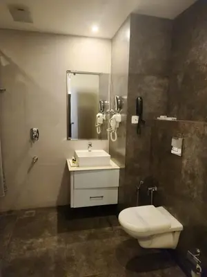 a bathroom with a toilet and a sink and a mirror at Le Sanara Residency in Thanniyam