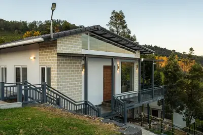 a home with a balcony and a house at Wattle Grove Resort in Kotagiri