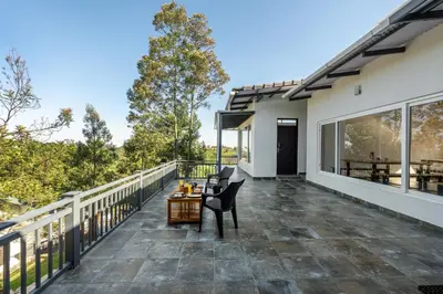 a patio with two chairs and a table on a balcony at Wattle Grove Resort in Kotagiri