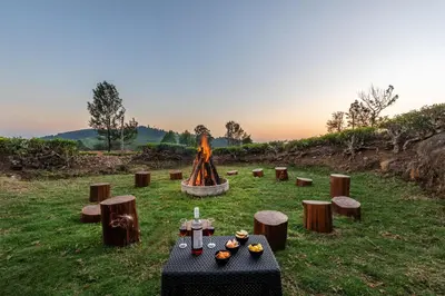 a woman standing in front of a fire in a field at Wattle Grove Resort in Kotagiri