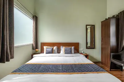 a bedroom with a large bed and a window at Wattle Grove Resort in Kotagiri