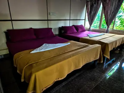 two beds and a couch in a room at Verdant Hillock in Wayanad