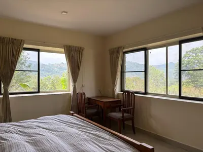 a bedroom with a bed and a table and windows at green home in Coonoor