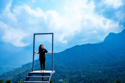 a woman is standing on a frame in the mountains at Nexstay Karimb Resorts in Vallikavungal