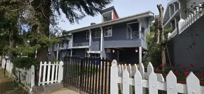 a white picket fence in front of a blue house at Fortune Retreats in Ooty