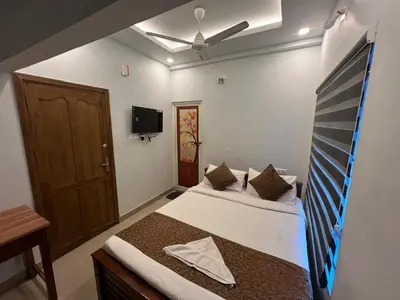 a bedroom with two beds and a tv on the wall at Confident Residency in Guruvāyūr