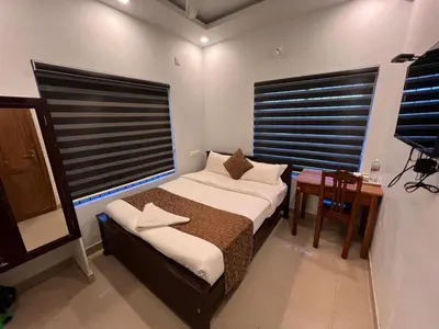 a bedroom with a bed and a table and a window at Confident Residency in Guruvāyūr