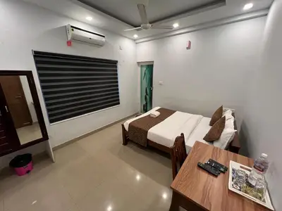 a bedroom with a bed and a table in a room at Confident Residency in Guruvāyūr