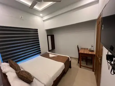 a bedroom with a bed and a desk and a television at Confident Residency in Guruvāyūr
