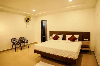 a bedroom with a bed and two chairs at GREEN MOUNT RESORTS in Malaiyāndipattanam