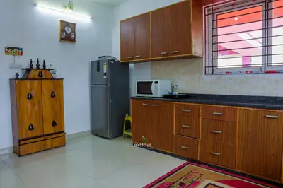 a kitchen with wooden cabinets and a stainless steel refrigerator at Green Premium Villa Ooty by Lexstays in Ooty