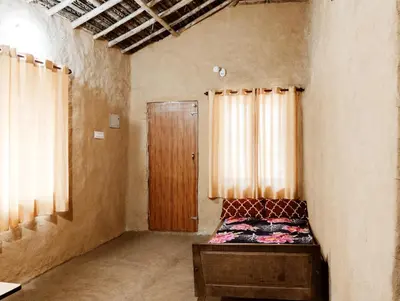 an empty room with a bed and a wooden door at Cosmic Mud House Kanthalloor in Kanthalloor
