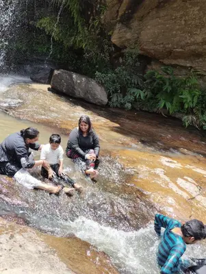 a group of people sitting in the water in a river at Cosmic Mud House Kanthalloor in Kanthalloor