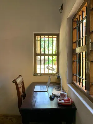a desk with a laptop computer on it in a room with a window at Shantam Homestay - Powered by Grackle in Cheruthuruthi