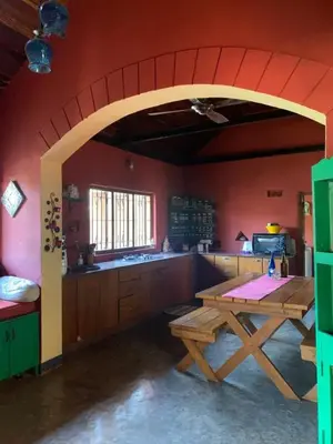 a kitchen with a wooden table and a red wall at Shantam Homestay - Powered by Grackle in Cheruthuruthi