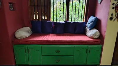 a red and green bench with pillows on top of it at Shantam Homestay - Powered by Grackle in Cheruthuruthi