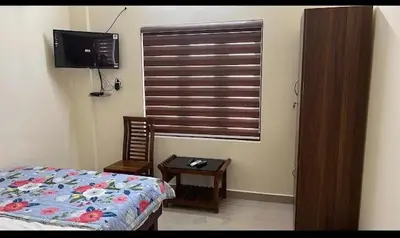 a bedroom with a bed and a table and a window at Manu's Home Stay in Malayāttūr