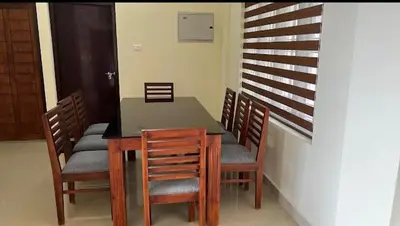 a dining room with a table and wooden chairs at Manu's Home Stay in Malayāttūr
