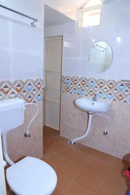 a bathroom with a sink and a toilet and a mirror at Coorg Lotus Villa in Madikeri