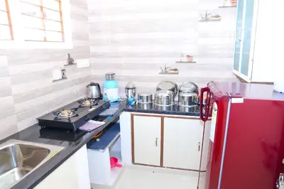 a kitchen with a red refrigerator next to a sink at Coorg Lotus Villa in Madikeri