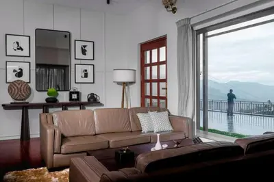 a living room with a couch and a large window at Nilgiri Valley Villa Ooty - a VKation Experience in Ooty