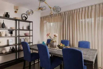 a dining room with a table and blue chairs at Nilgiri Valley Villa Ooty - a VKation Experience in Ooty